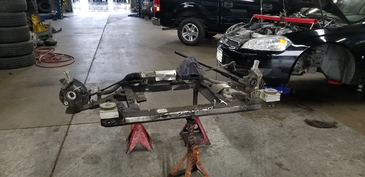 Inside the Southland Automotive workshop, a subframe and steering rack on jack stands with a car up on the lift behind